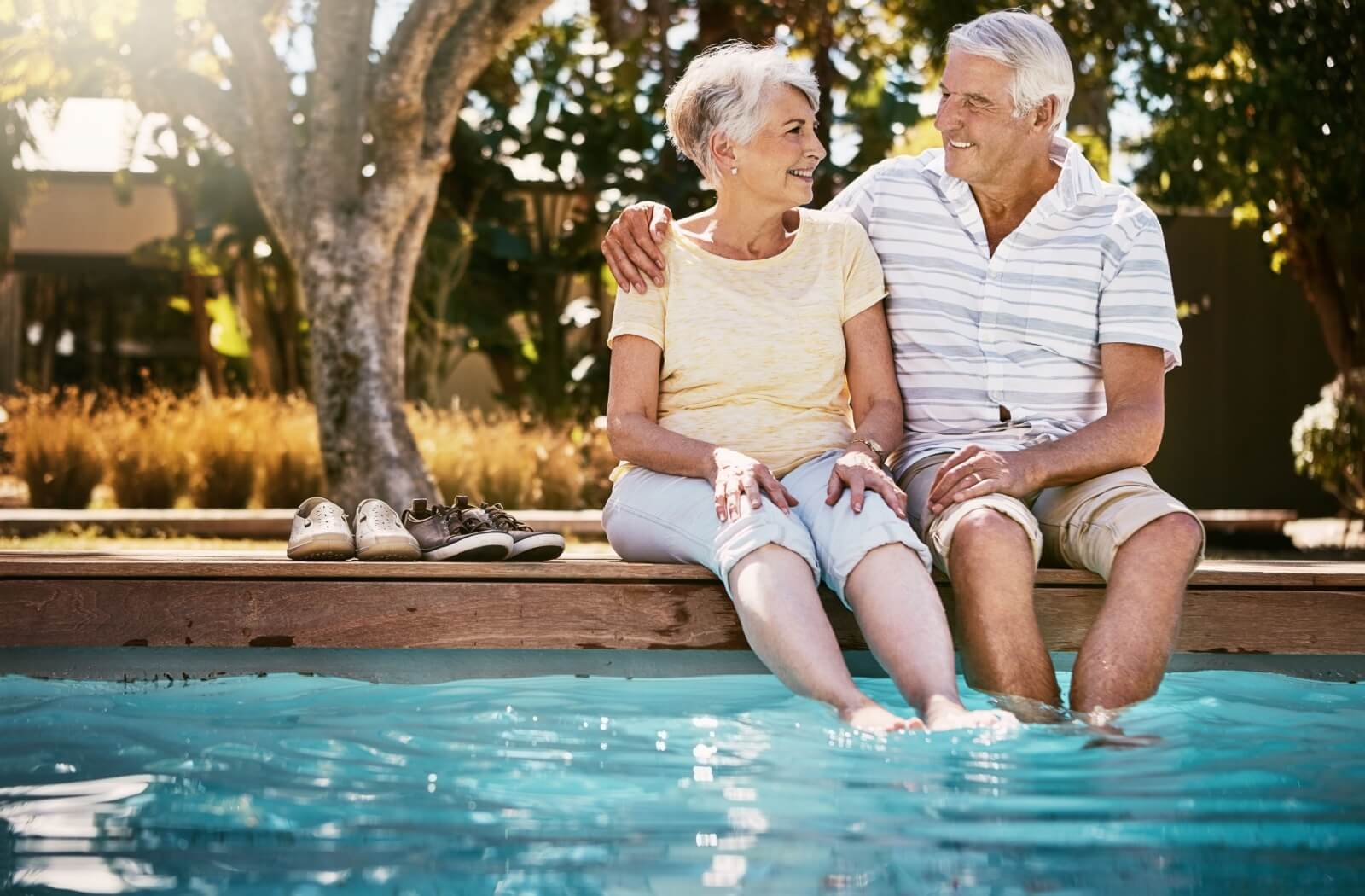 a senior couple cooling their feet in a swimming pool