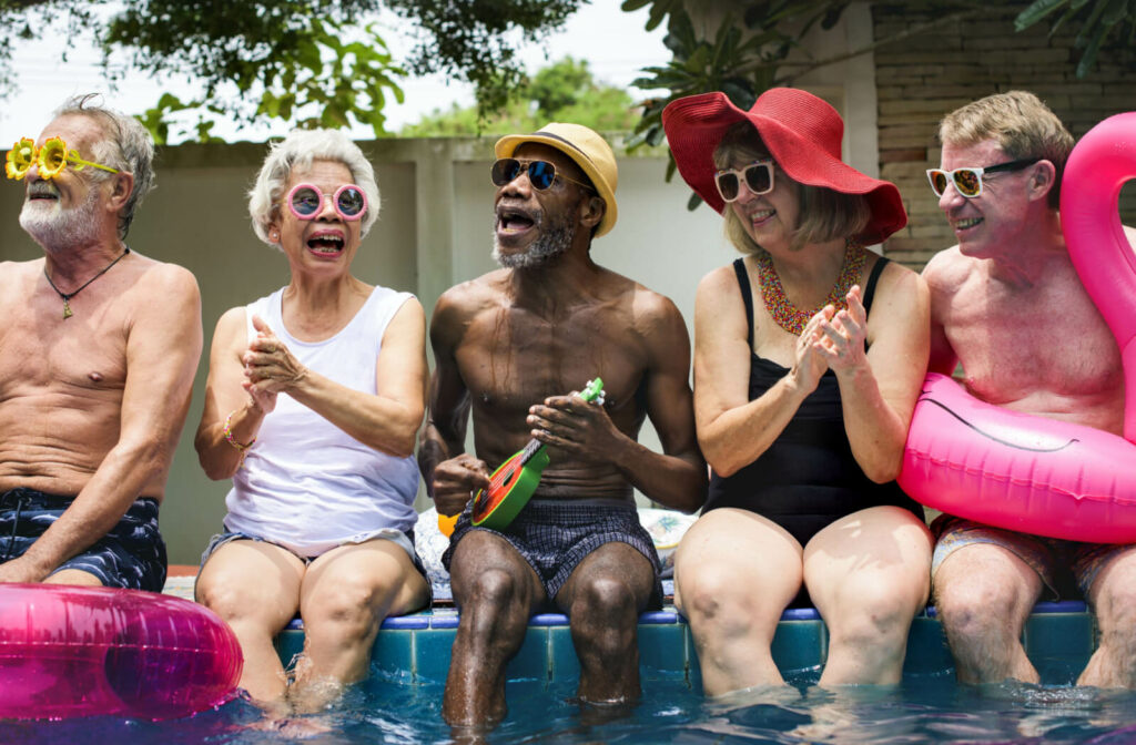 A group seniors sitting by the pool, smiling and laughing together