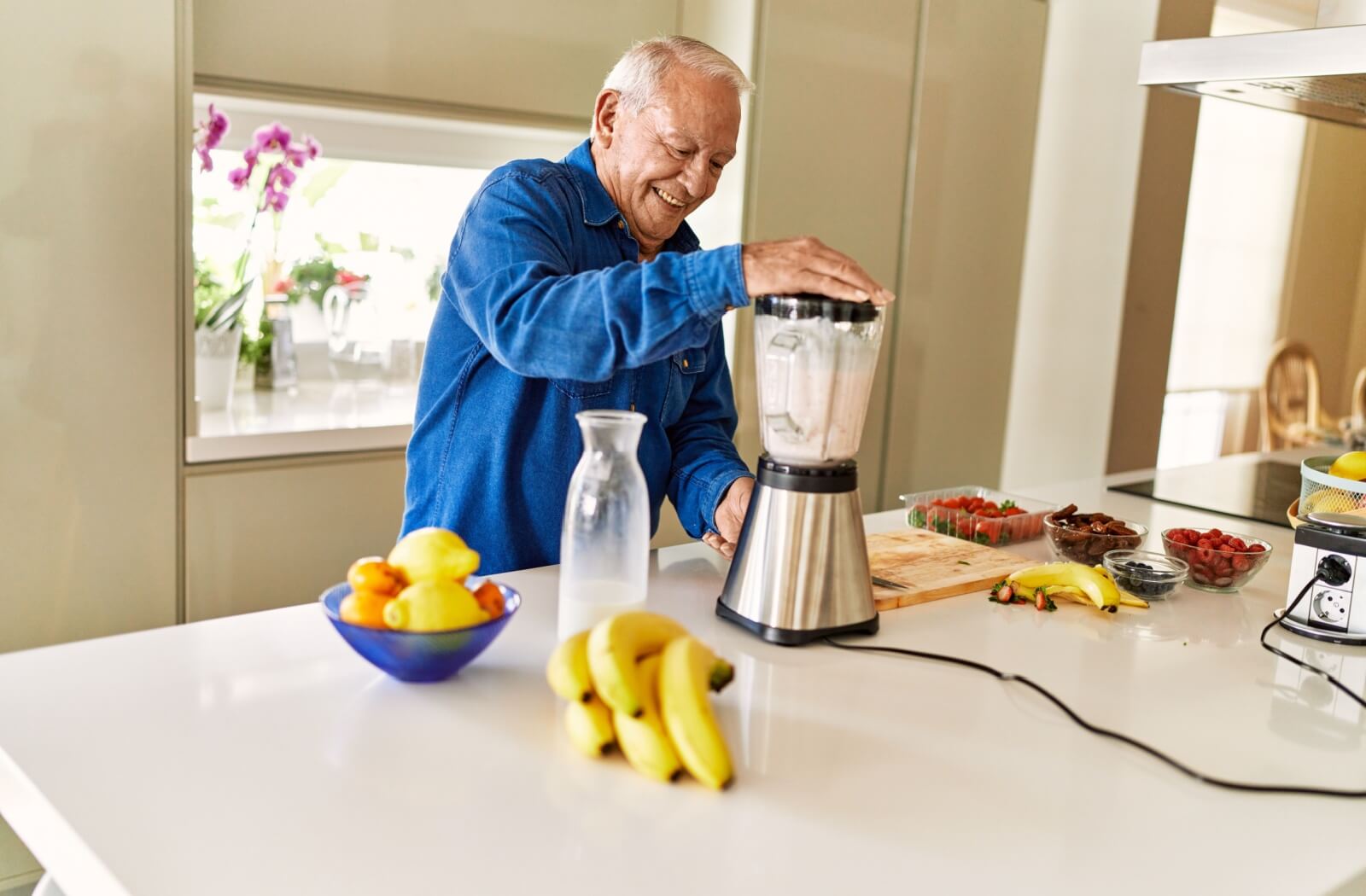 A happy senior use protein powder to make a healthy fruit smoothie.